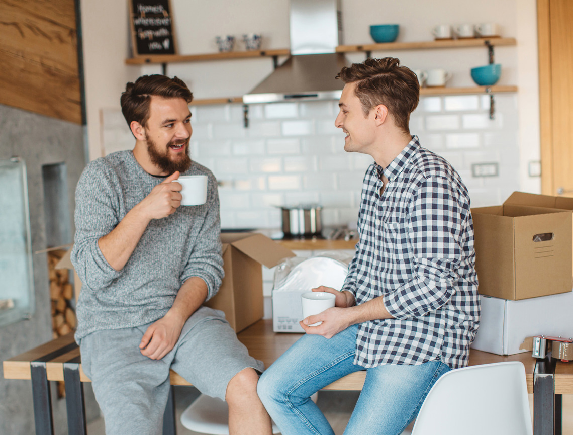To unge mænd der snakker og drikker kaffe